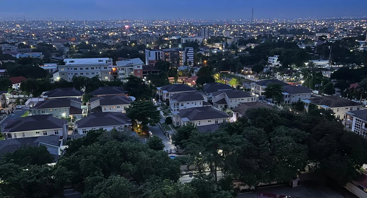 Accra neighbourhood at dusk with city lights in the distance